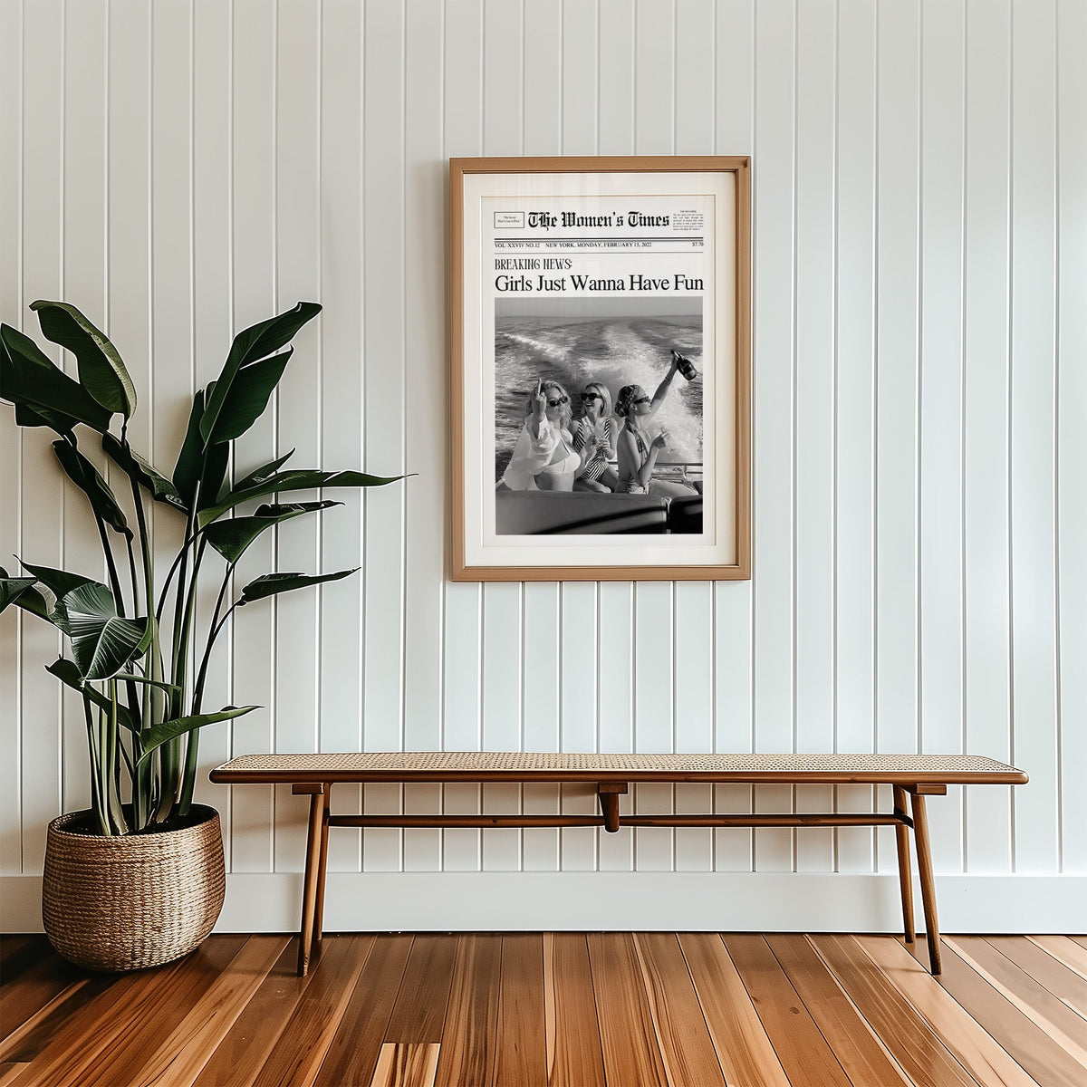 Mock front page with three women on a yacht print in a wood frame with a white mat above a cane bench