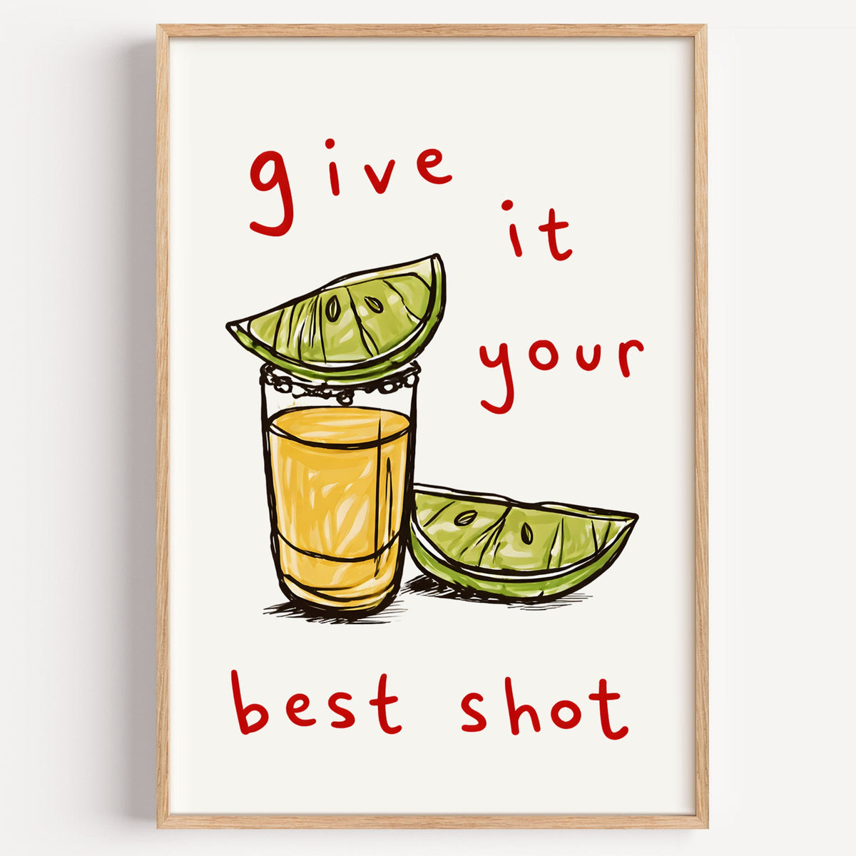 Give It Your Best Shot tequila print in a light oak frame on a plain white wall