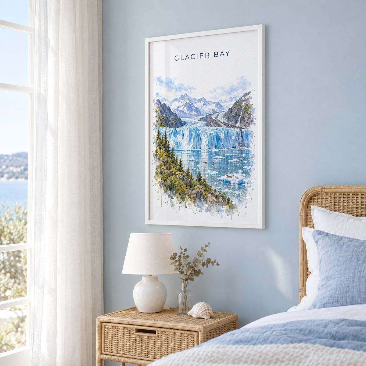Glacier Bay National Park watercolor print in a white frame on a pale blue wall beside a rattan bed in a coastal bedroom