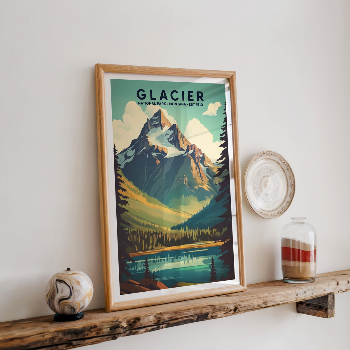 Glacier National Park print in an oak frame on a rustic wood shelf with ceramics and a sand-filled jar