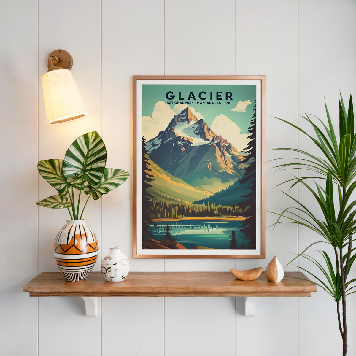 Glacier National Park print in a copper frame above an oak shelf on white shiplap with a brass sconce
