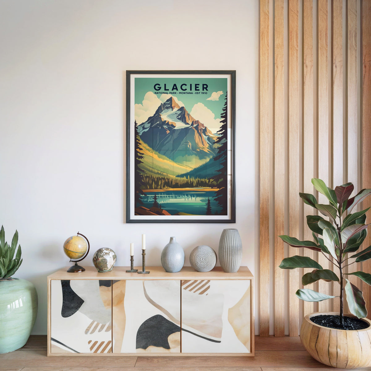 Glacier National Park print in a black frame above a light wood sideboard with a globe and ceramic vases
