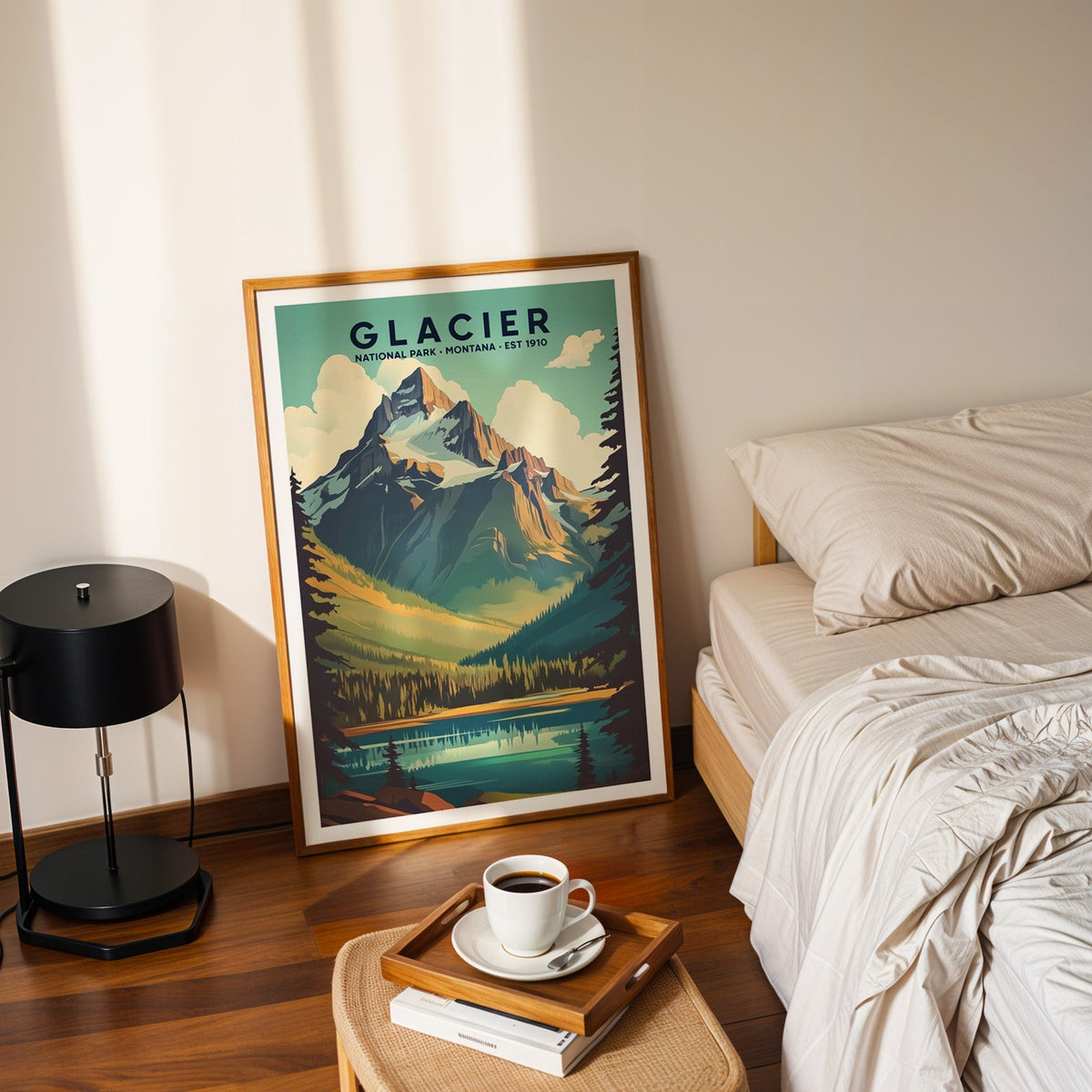 Glacier National Park print in an oak frame leaning on a bedroom floor beside the bed and a coffee tray