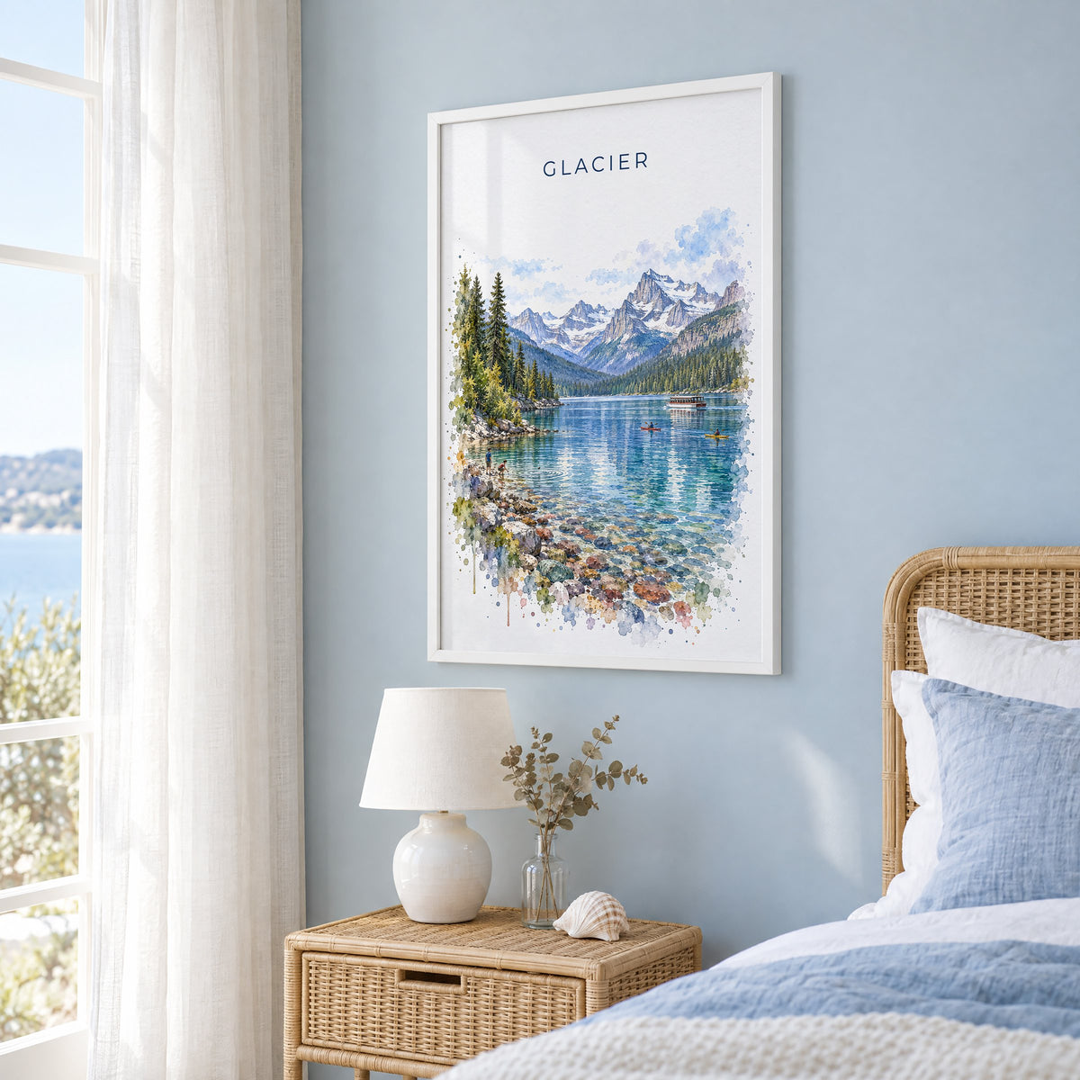 Glacier National Park watercolor print in a white frame on a pale blue wall beside a rattan bed in a coastal bedroom