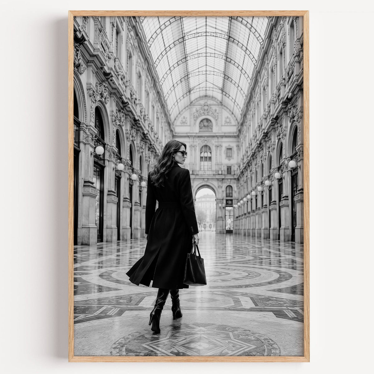Black and white woman in a glass arcade print in a light oak frame on a plain white wall