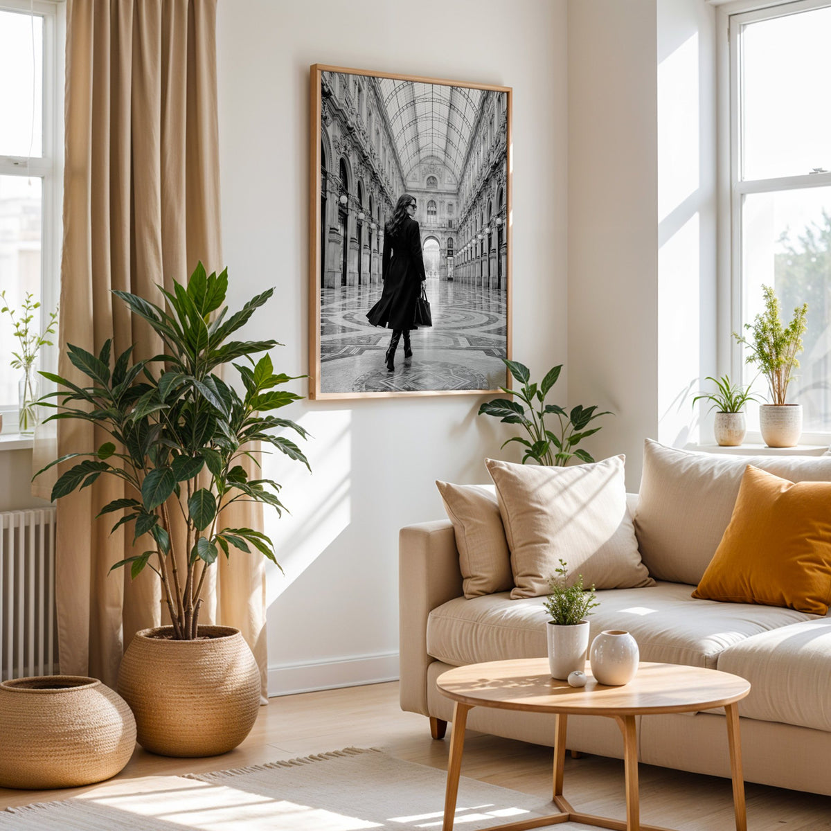 Black and white woman in a glass arcade print in an oak frame above a cream sofa beside woven planters