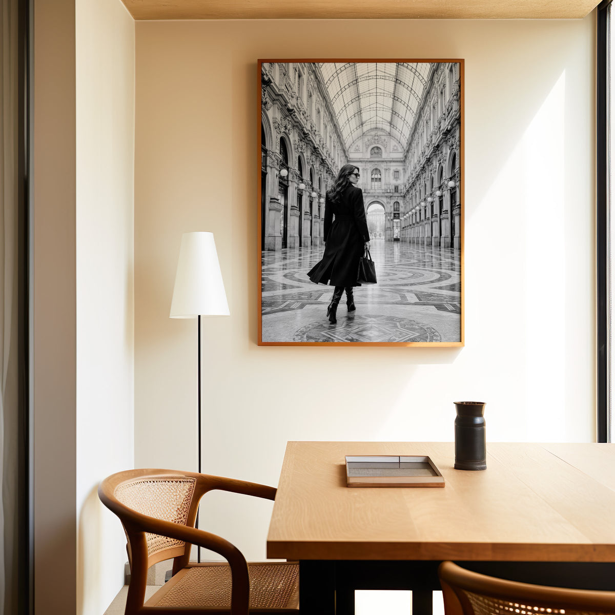 Black and white woman in a glass arcade print in an oak frame above a dining table and cane chair