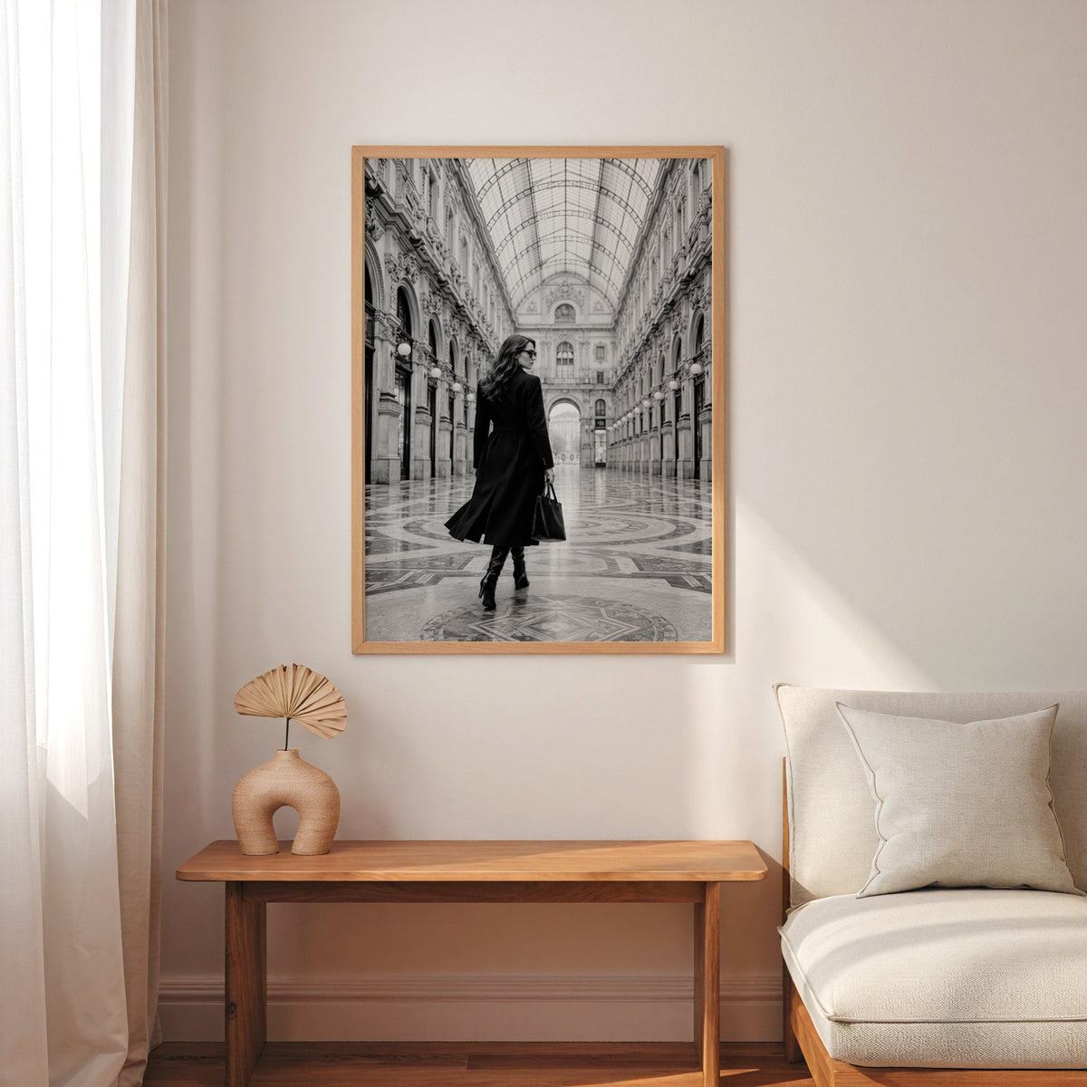 Black and white woman in a glass arcade print in an oak frame above a narrow console with an arched vase