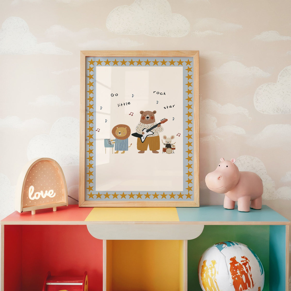 Go little rock star band nursery print in an oak frame on a rainbow toy shelf against cloud wallpaper