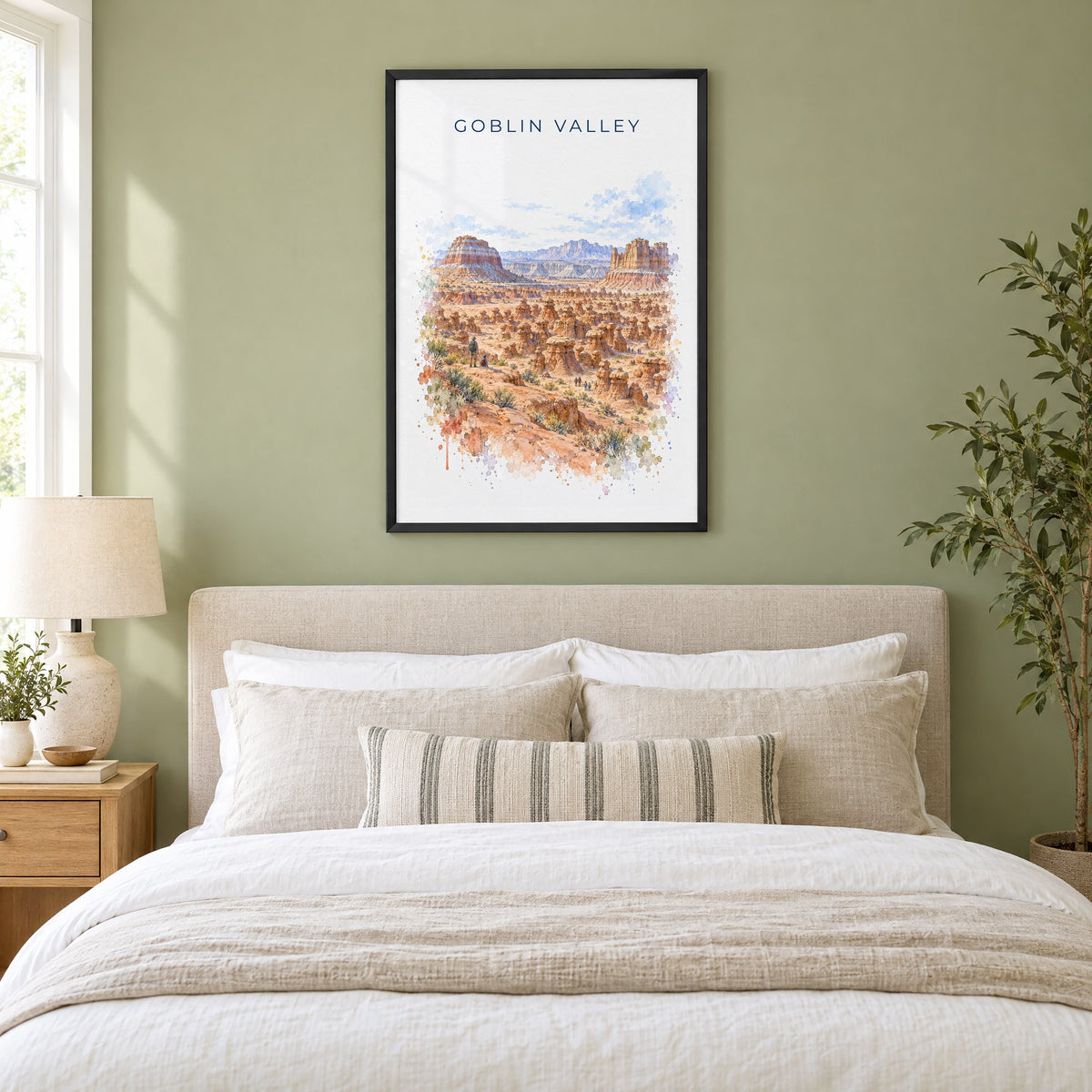 Goblin Valley State Park watercolor print in a black frame above an upholstered headboard in a sage green bedroom