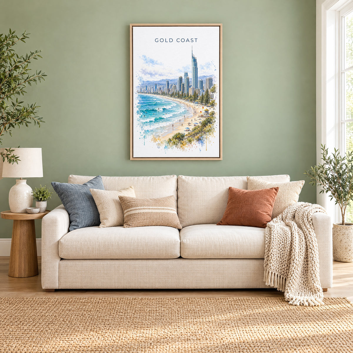 Gold Coast watercolor print as a natural floater canvas above a cream linen sofa on a sage green wall