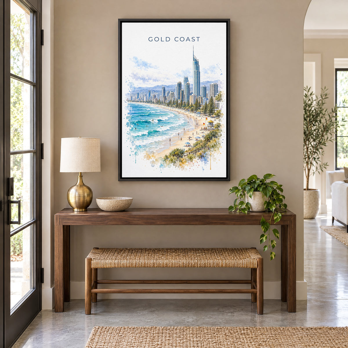 Gold Coast watercolor print as a black floater canvas above a walnut console and woven bench in an entryway
