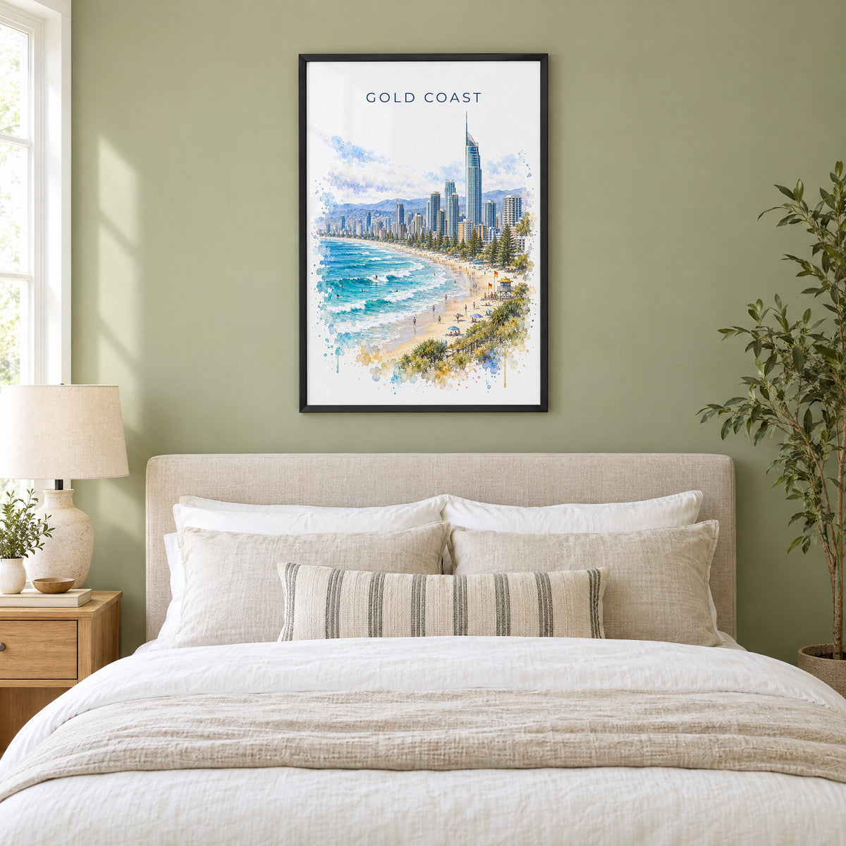 Gold Coast watercolor print in a black frame above an upholstered headboard in a sage green bedroom
