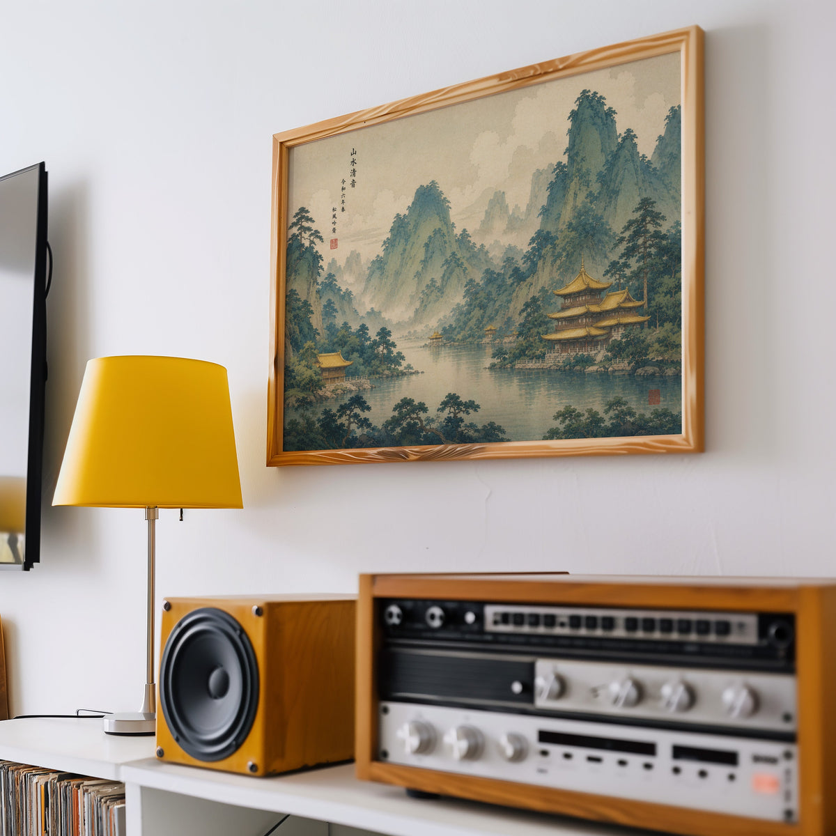 Golden temples below green mountains print in a pine frame above a vintage stereo and a yellow table lamp