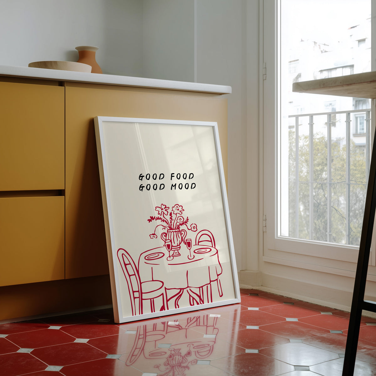 Good Food Good Mood print in a white frame against yellow cabinets on red tiles