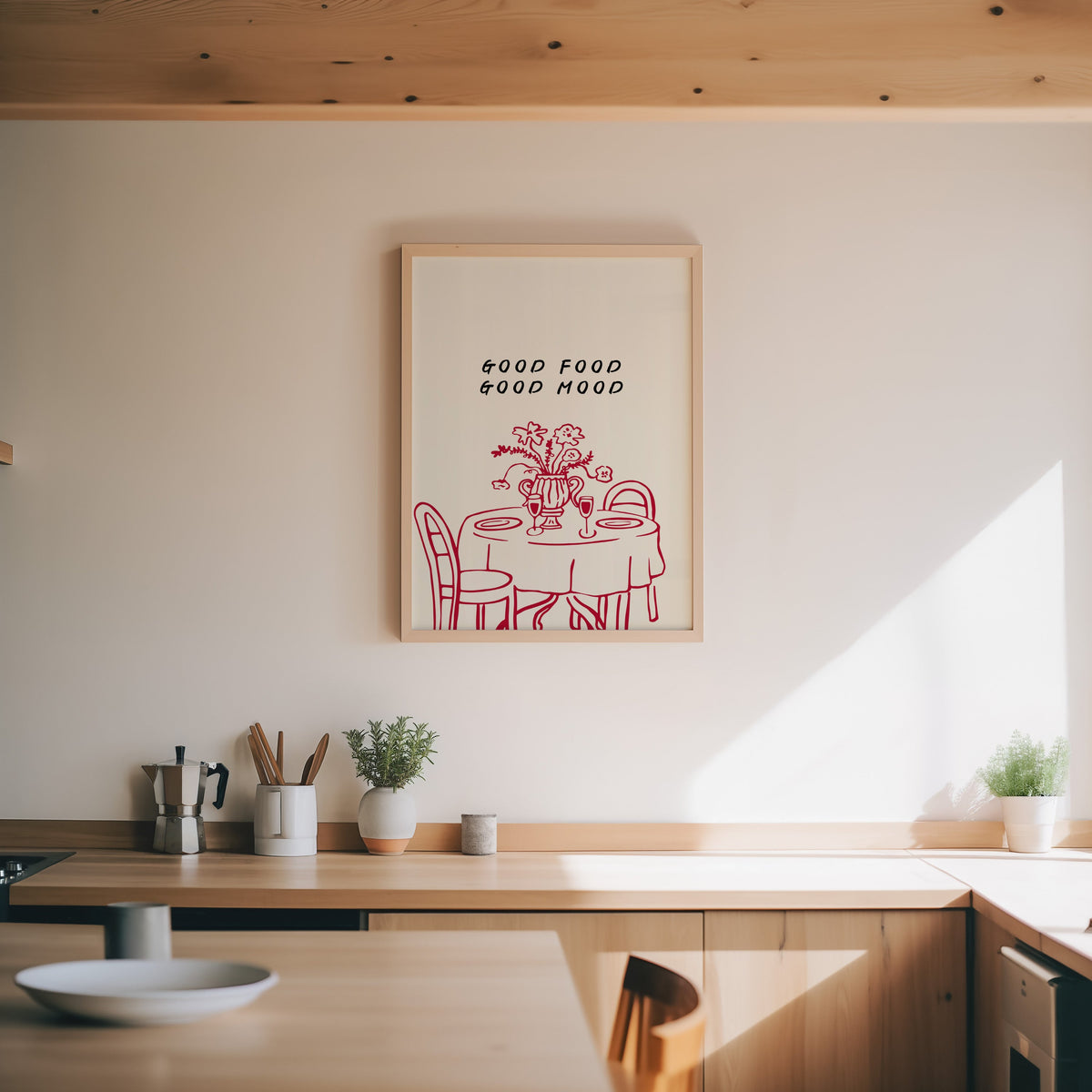 Good Food Good Mood print in an oak frame above a wood counter with a moka pot