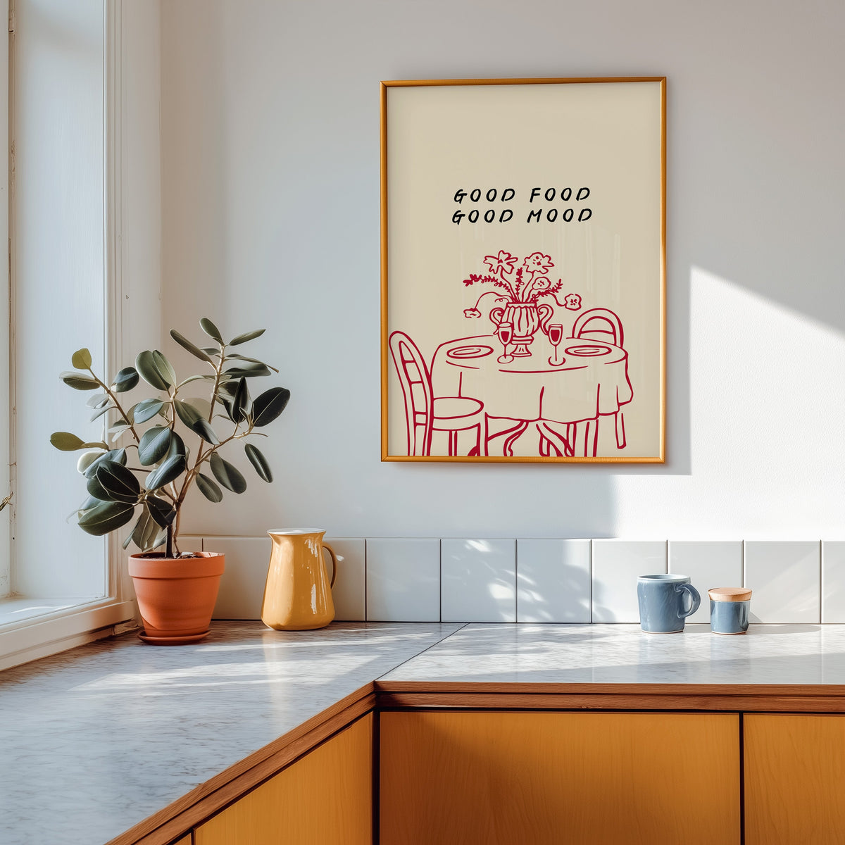 Good Food Good Mood print in a gold frame above a marble counter with a yellow jug