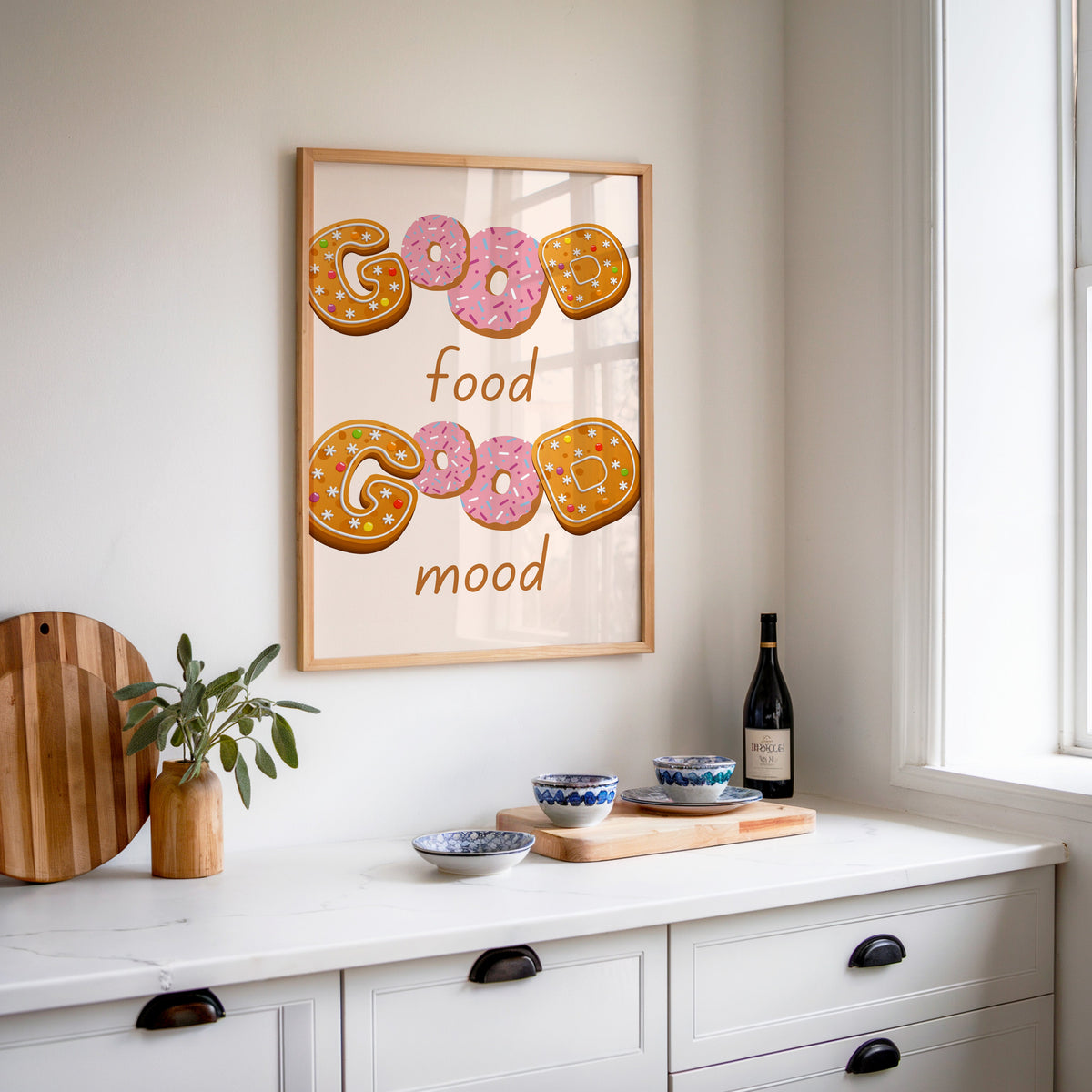 Good Food Good Mood donut print in an oak frame above a white sideboard with a bottle of wine