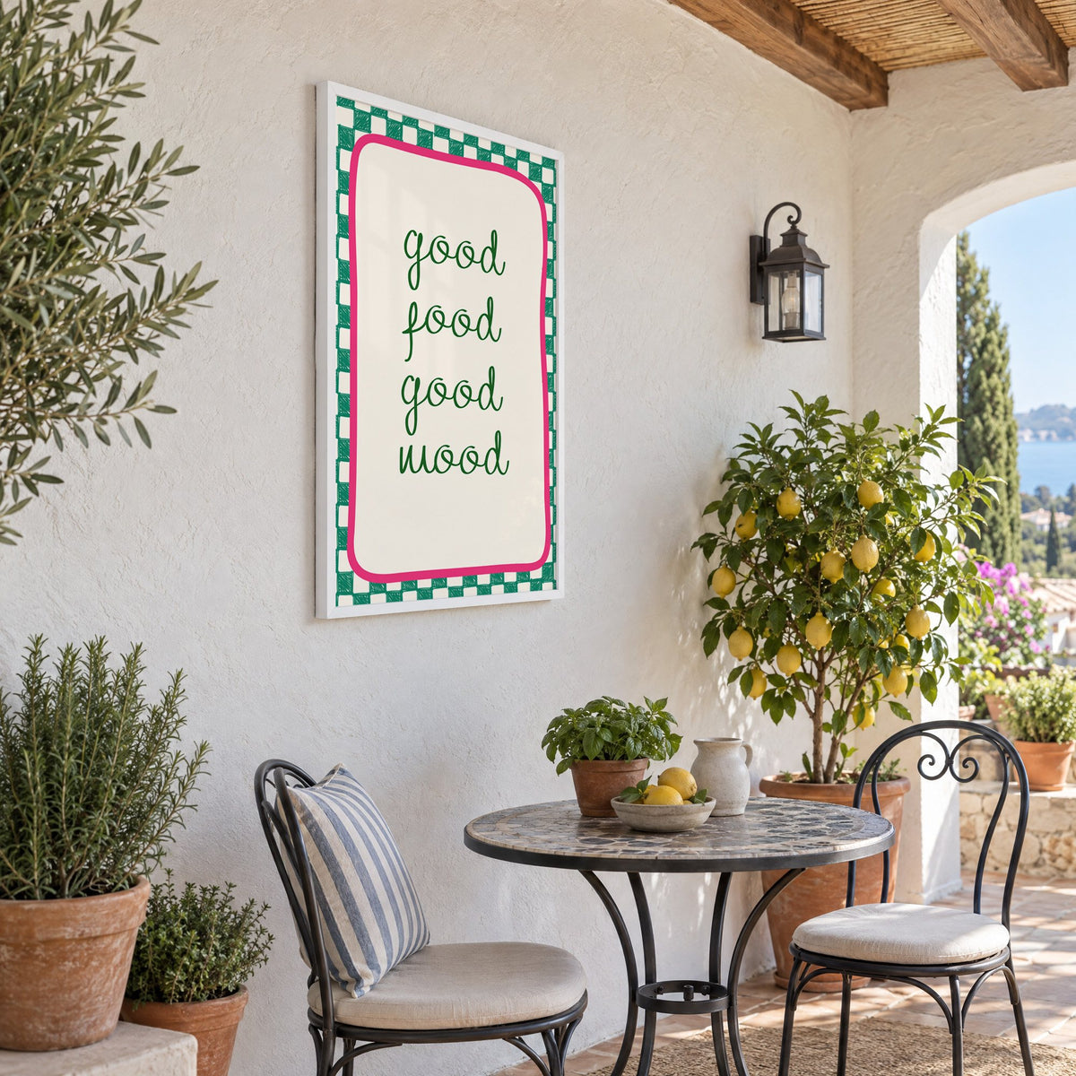 Good food good mood checkered print in a white frame on a sunny patio wall beside a potted lemon tree