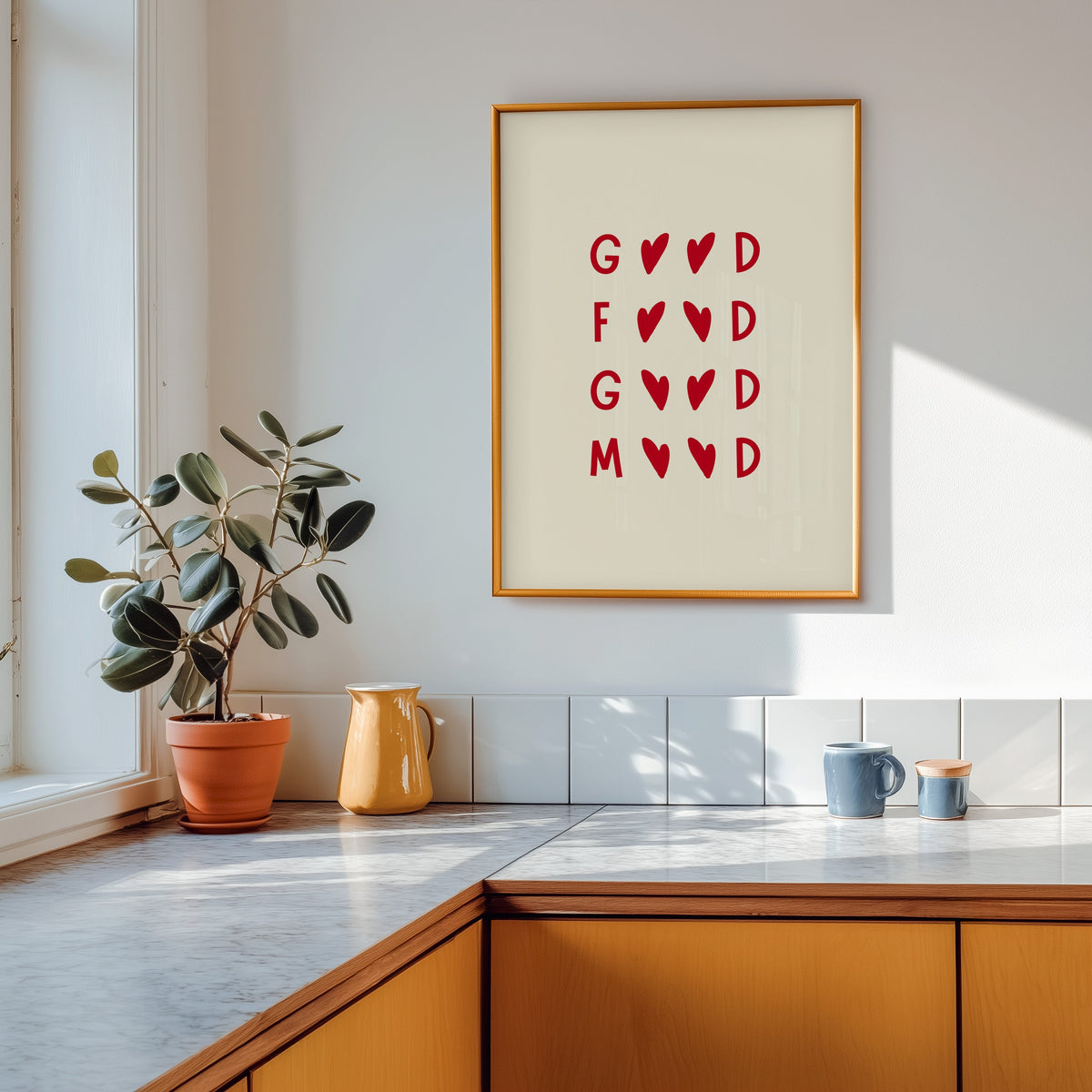 Good Food Good Mood print shown in a gold frame above a marble counter with a yellow ceramic jug