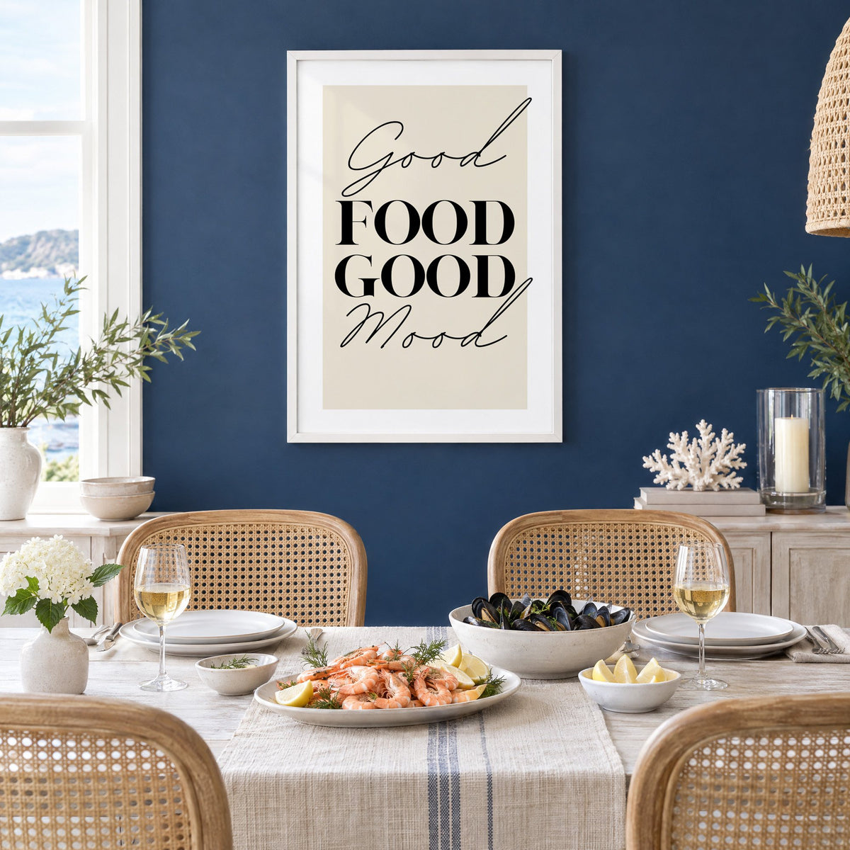 Good FOOD GOOD Mood serif script print in a white frame on a navy wall above a dining table set with shrimp and mussels