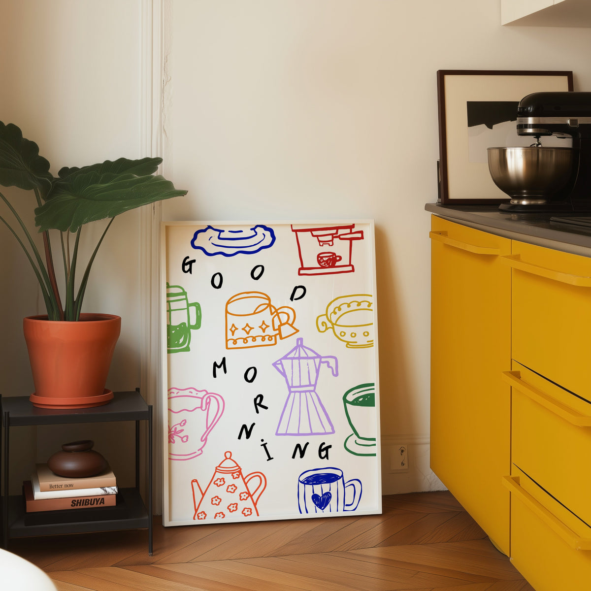 Good Morning coffee print in a white frame leaning on parquet beside a bright yellow kitchen