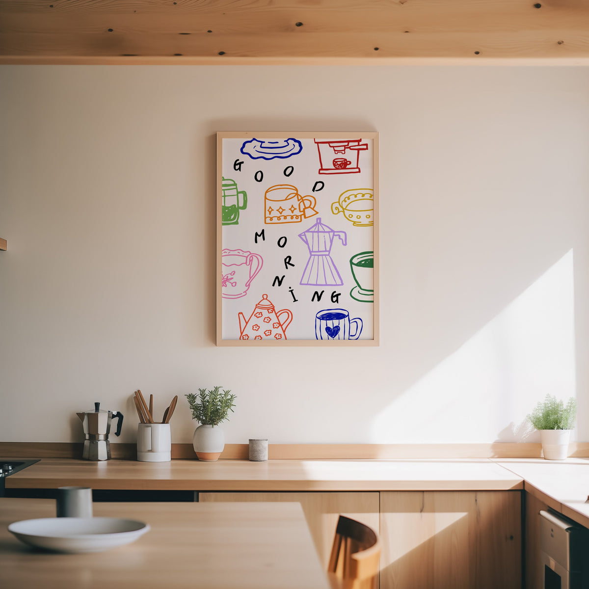 Good Morning coffee print in an oak frame above a wood counter with a moka pot and herbs