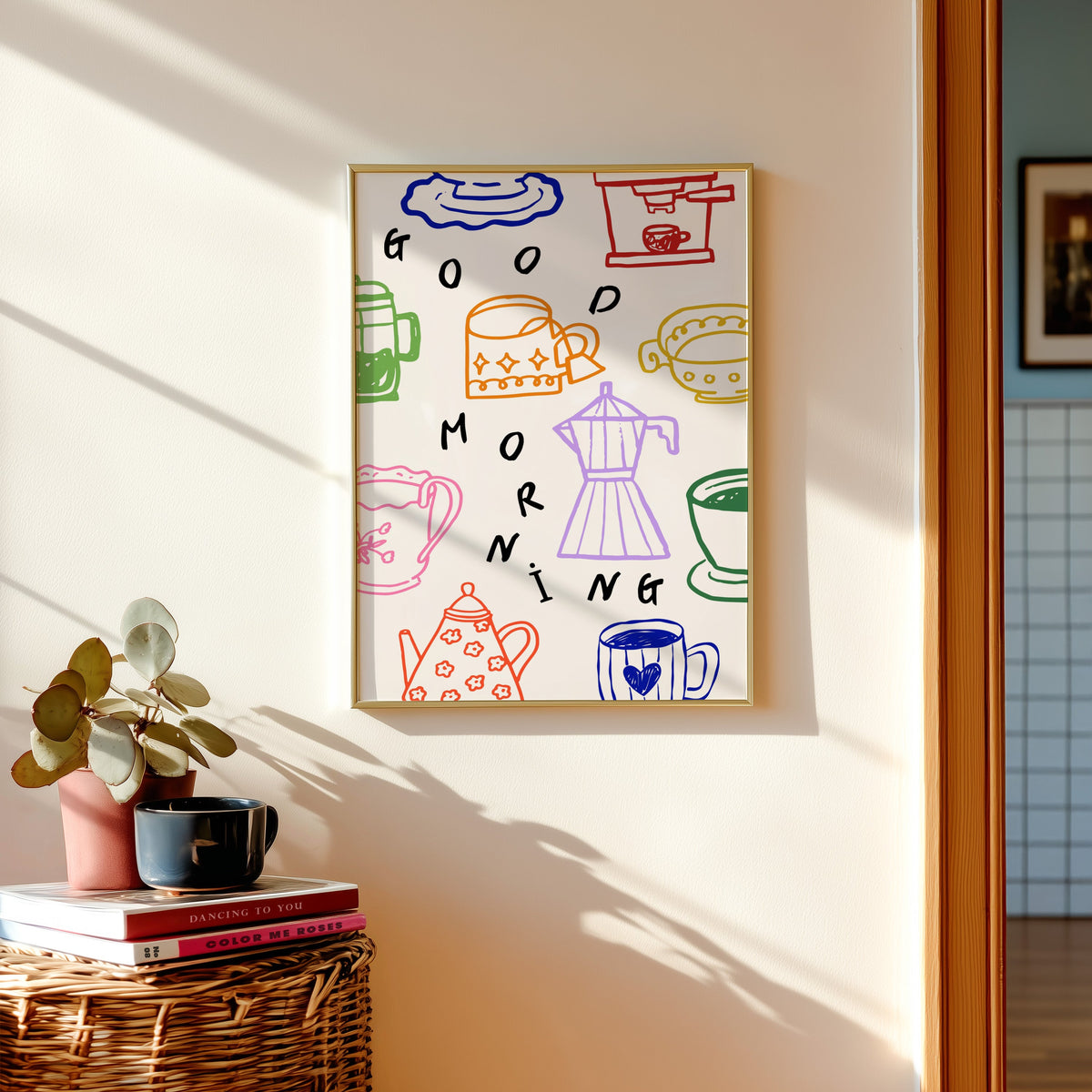 Good Morning coffee print shown in a gold frame above a basket of books and a pilea plant