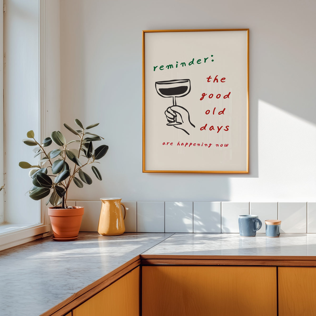 Good Old Days print shown in a gold frame above a marble counter with a yellow ceramic jug