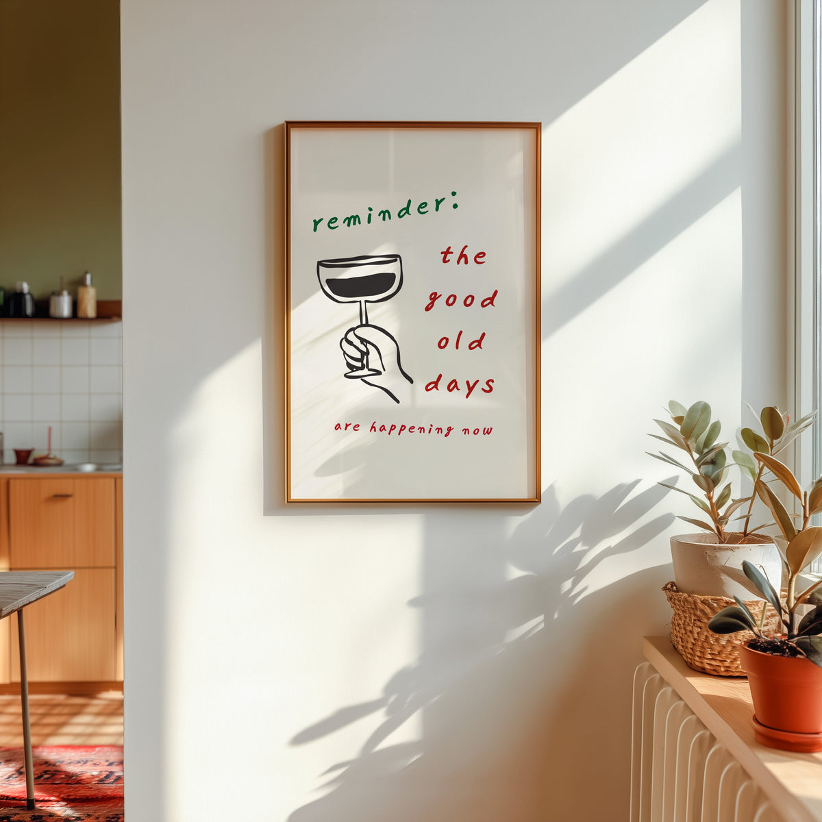 Good Old Days print shown in a gold frame in sunlight with plants and a kitchen beyond