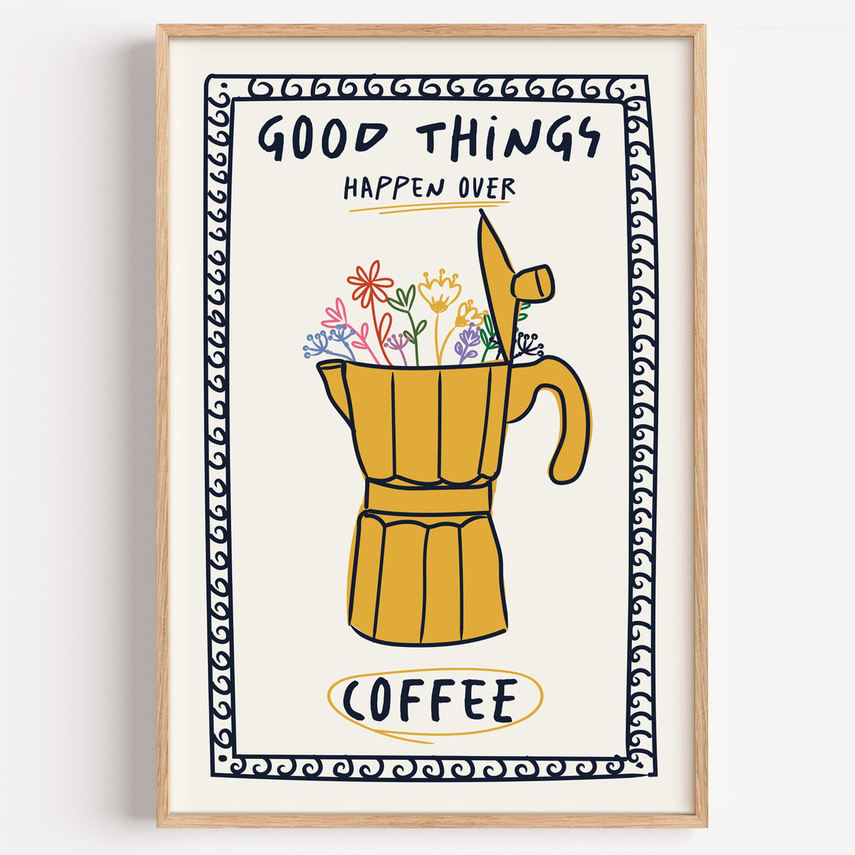 Good things happen over coffee print in a light oak frame on a plain white wall