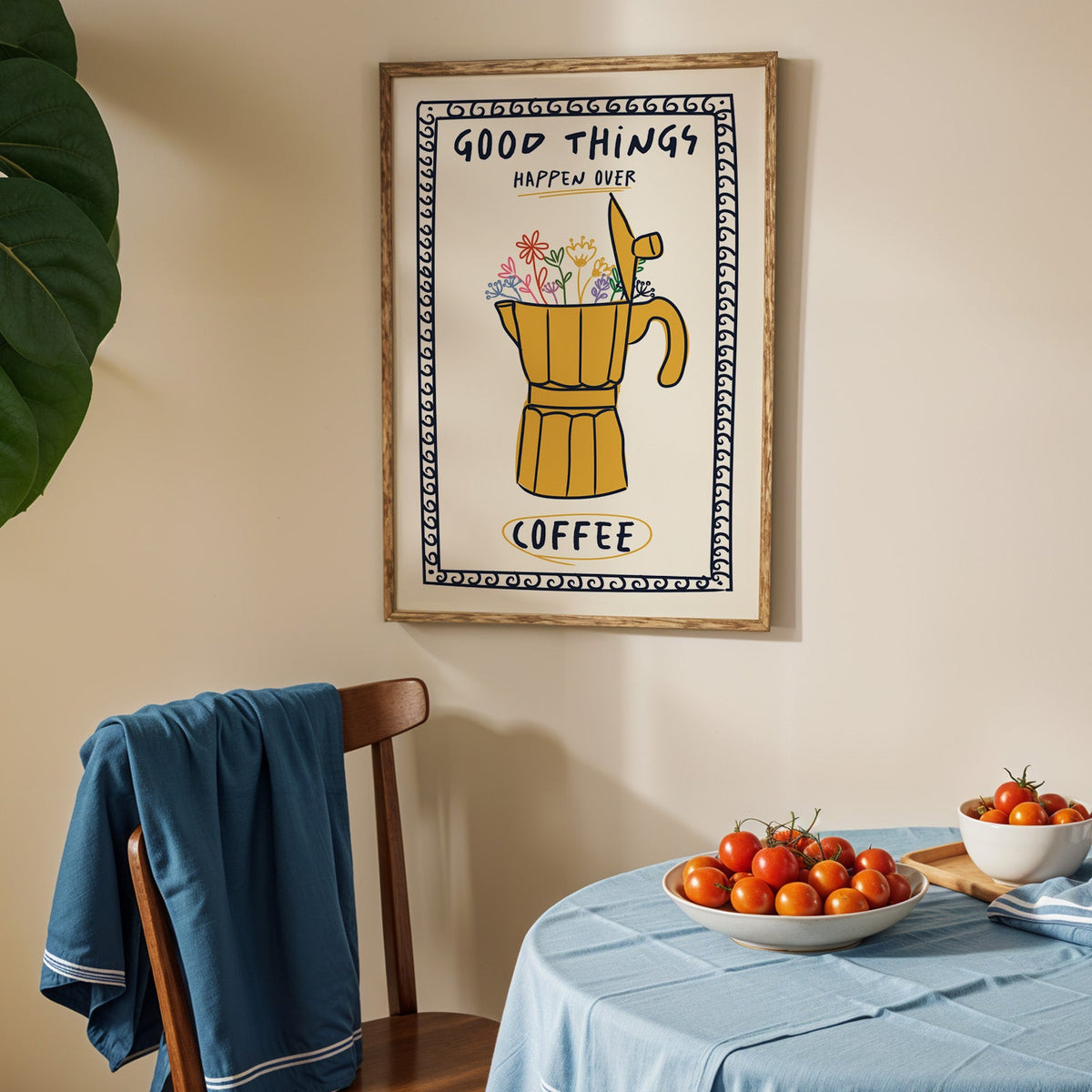 Good things happen over coffee print in an oak frame above a blue linen table with tomatoes