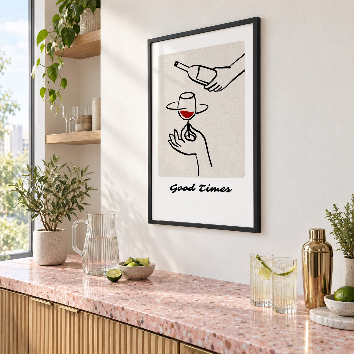 Good Times wine pour line art print in a black frame above a pink terrazzo cocktail counter with limes, seen at an angle
