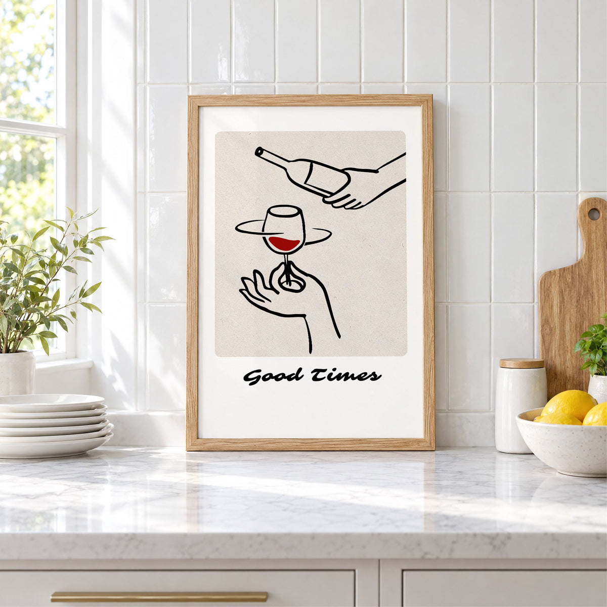 Good Times wine pour line art print in an oak frame leaning on a marble counter by white tiles and lemons