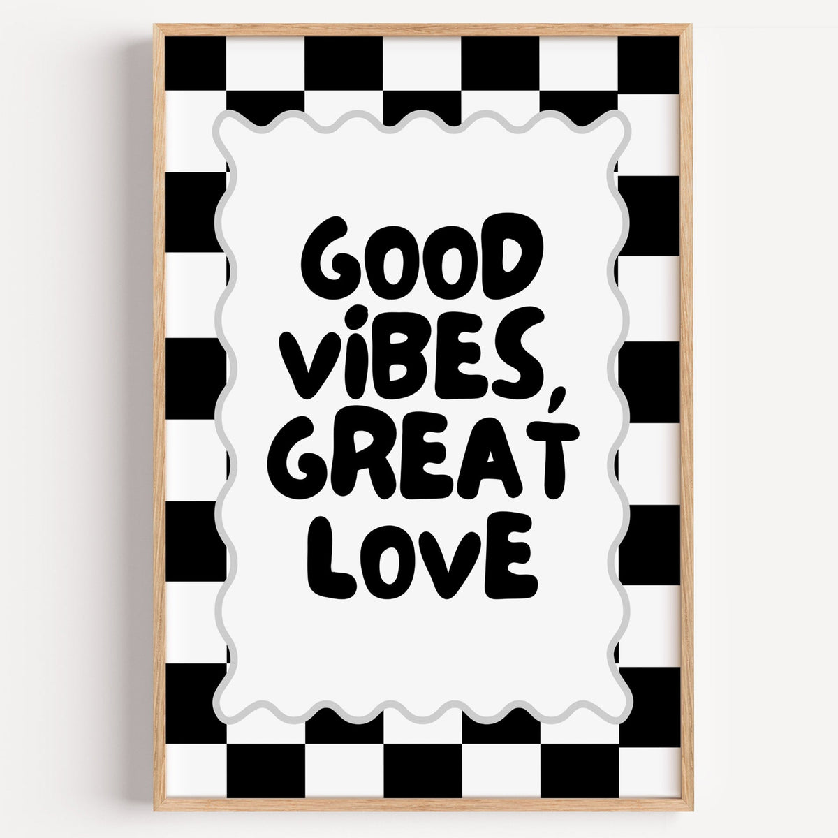 Good vibes great love checkerboard quote print in a light oak frame on a plain white wall