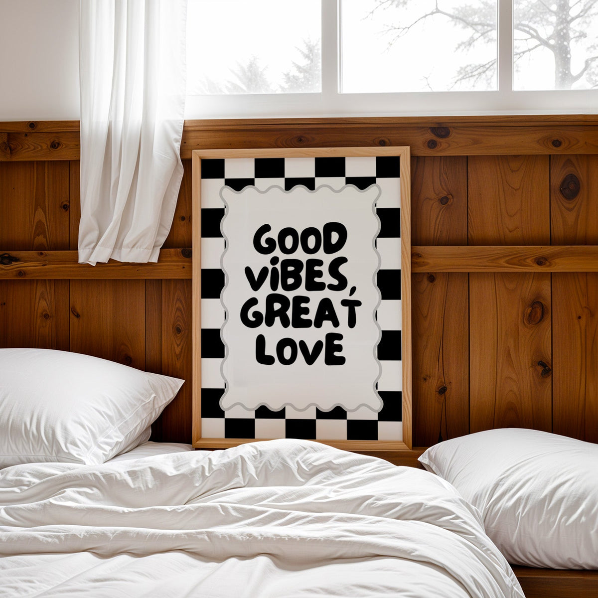 Good vibes great love checkerboard quote print in a pine frame leaning on a wood headboard over white bedding