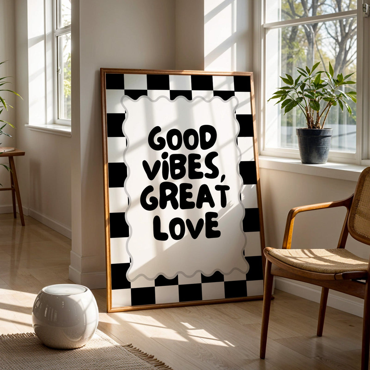 Good vibes great love checkerboard quote print in a walnut frame on a wood floor beside a cane chair and sunny window