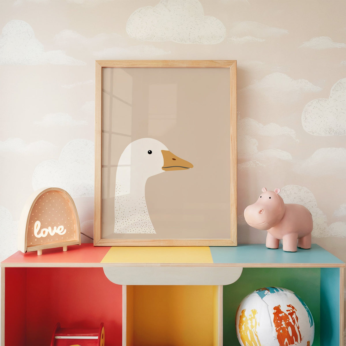 Goose head profile nursery print in an oak frame on a rainbow toy shelf against cloud wallpaper