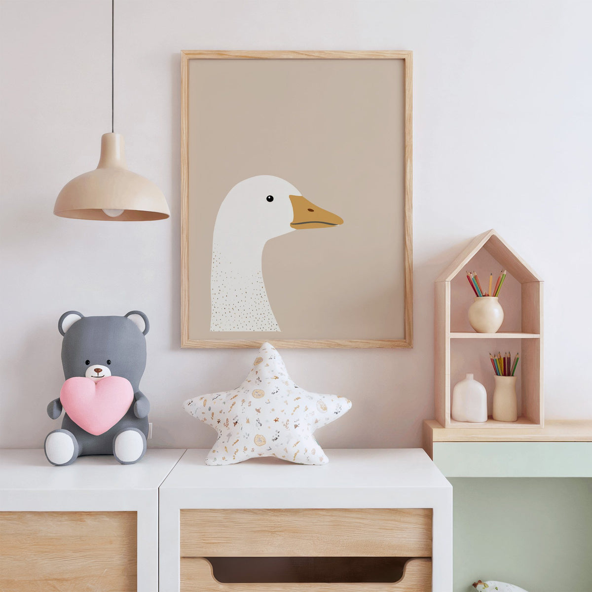 Goose head profile nursery print in an oak frame above a white dresser with a star pillow and house shelf