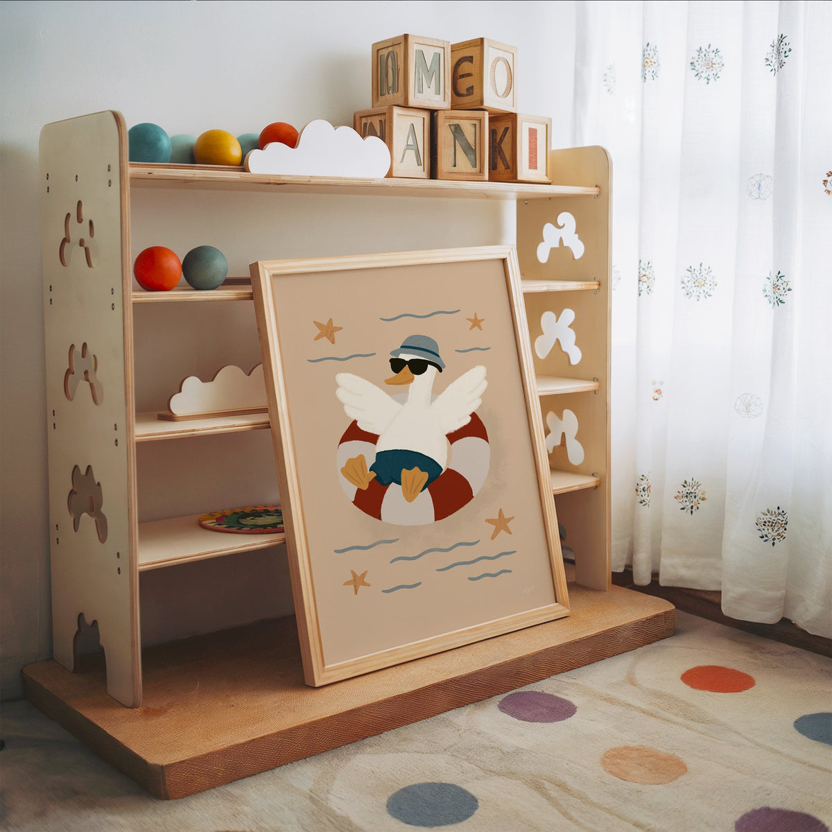 Goose in lifesaver ring nursery print in an oak frame leaning on a toy shelf with wooden letter blocks