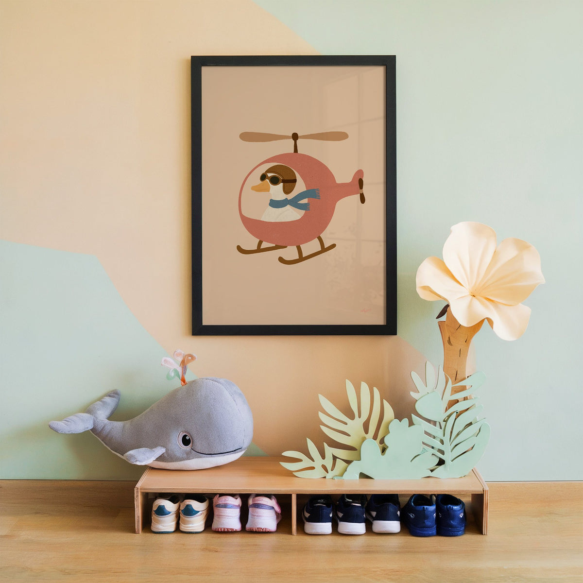 Goose pilot in pink helicopter nursery print in a black frame on a mint and peach wall above a whale plush