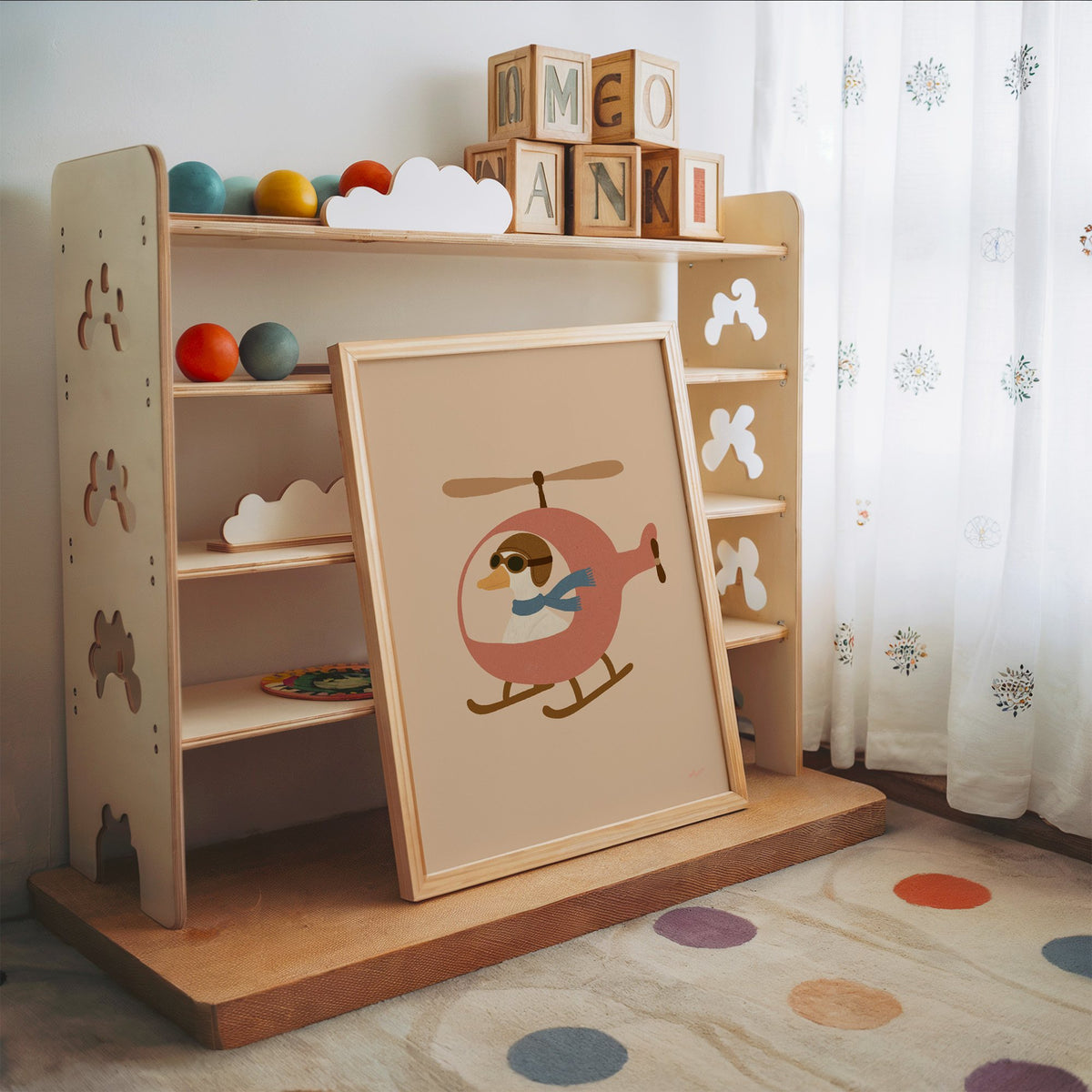 Goose pilot in pink helicopter nursery print in an oak frame leaning on a toy shelf with wooden letter blocks
