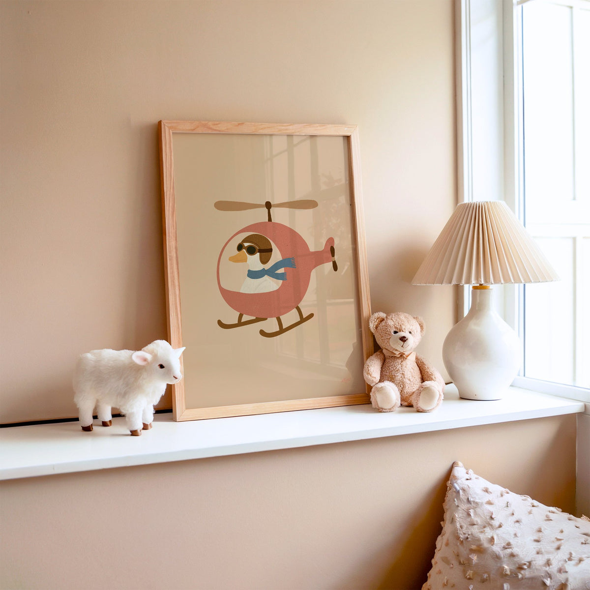 Goose pilot in pink helicopter nursery print in an oak frame on a window ledge with a toy lamb and teddy