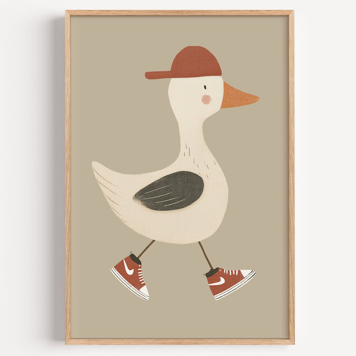 Goose red cap and sneakers nursery print in a light oak frame on a plain white wall