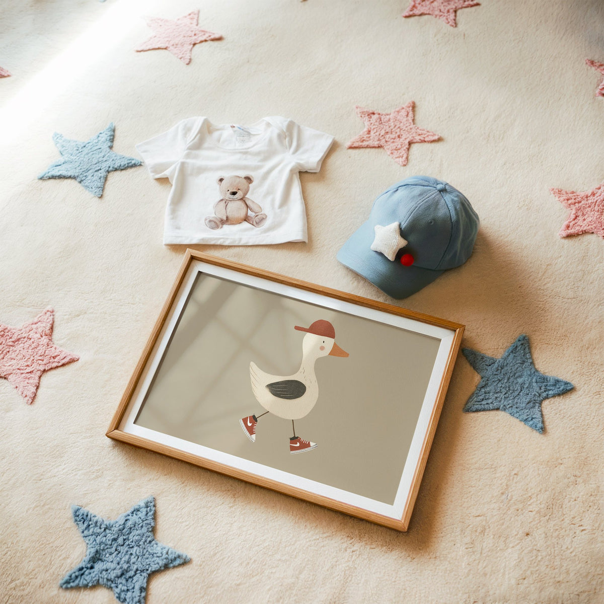Landscape goose red cap and sneakers nursery print in a matted oak frame on a star rug with a baby tee