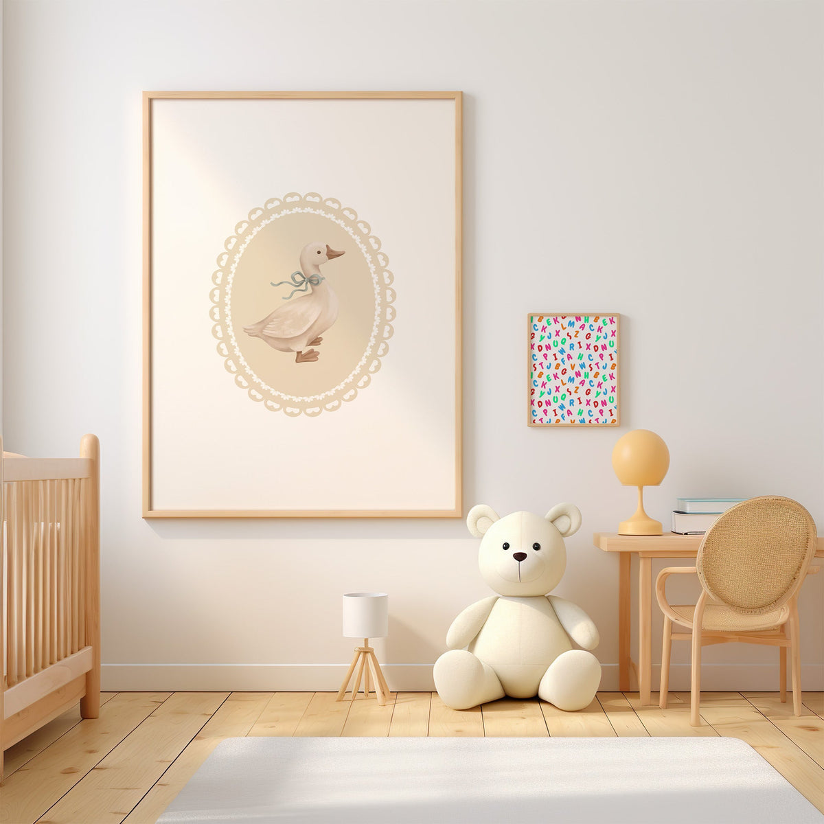 Goose with sage ribbon in heart lace oval nursery print in an oak frame above a wooden crib beside a cream teddy bear