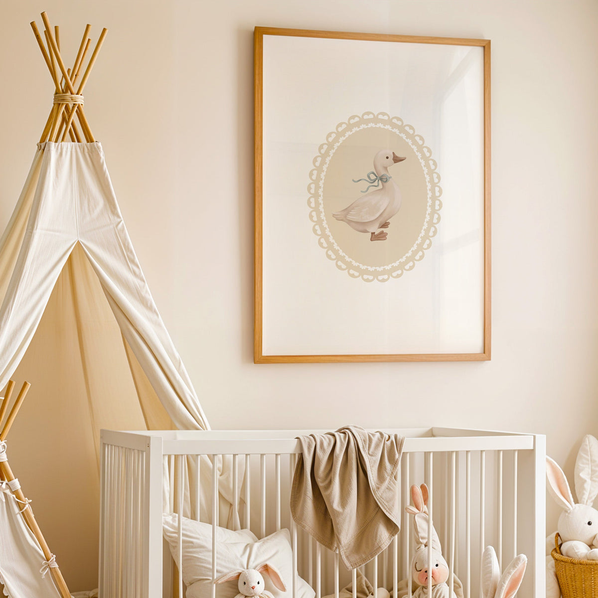 Goose with sage ribbon in heart lace oval nursery print in an oak frame above a white crib beside a canvas teepee