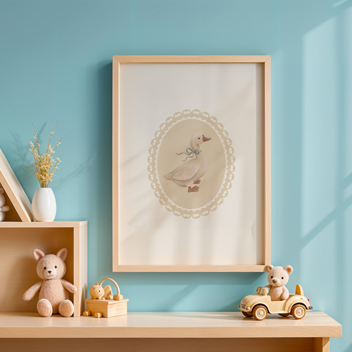 Goose with sage ribbon in heart lace oval nursery print in an oak frame on a blue wall above a shelf of wooden toys