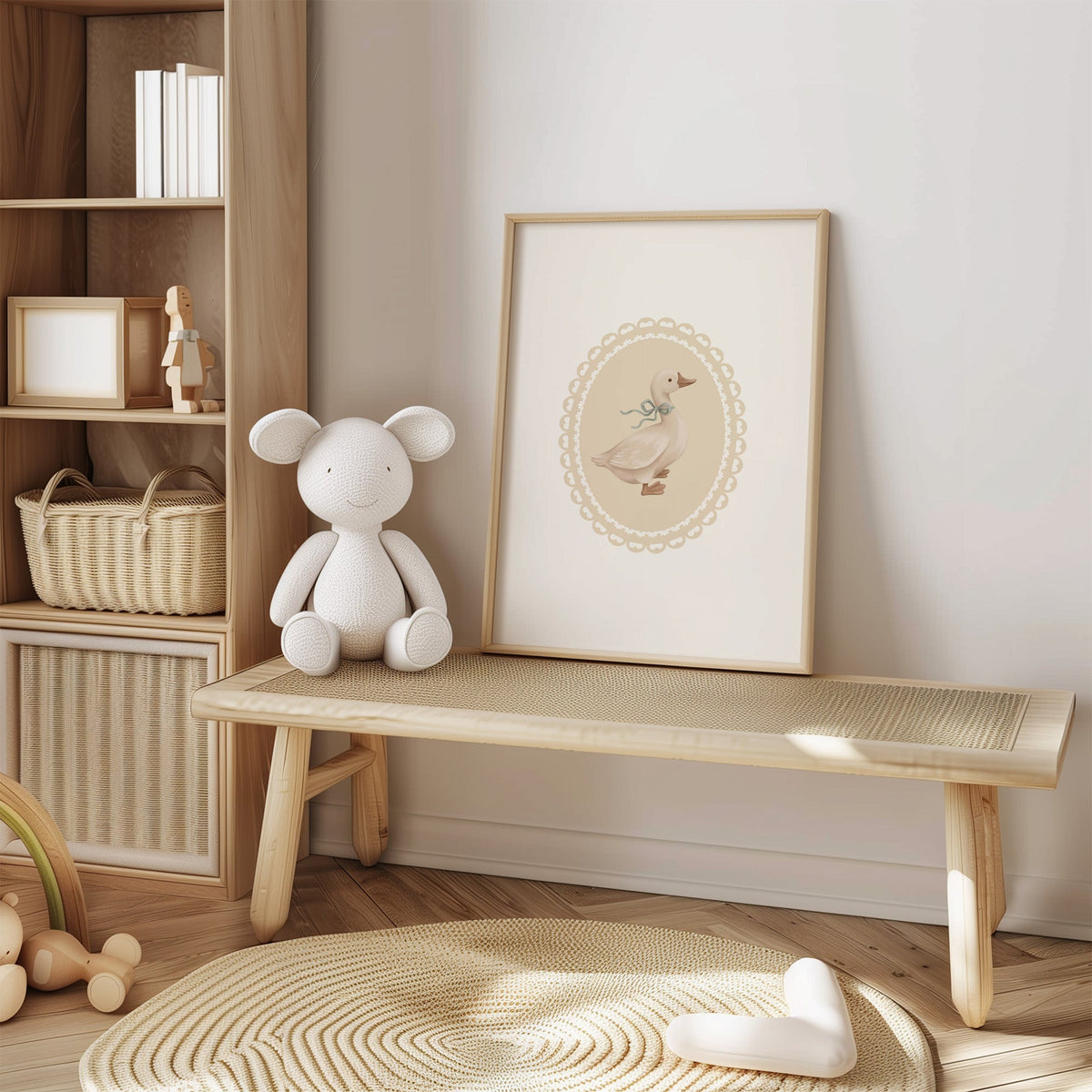 Goose with sage ribbon in heart lace oval nursery print in an oak frame on a cane bench beside a white knit plush