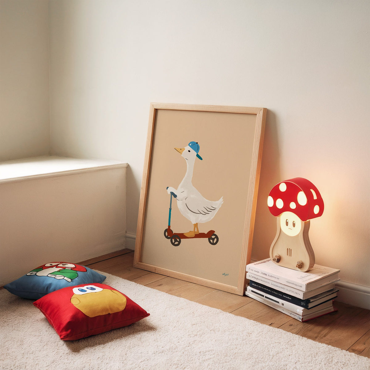 Goose riding scooter in blue cap nursery print in an oak frame leaning on a rug beside a mushroom lamp and floor cushions